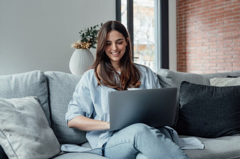 Concentrated,Millennial,Girl,Sit,On,Couch,Working,On,Laptop,Browsing